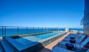 Una piscina infinita en la azotea con vistas despejadas al océano y al horizonte de la ciudad.