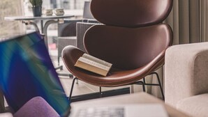 A modern chair with a book on it, a small table with a plant, and a window with curtains. - Puro - Modern Apartment by the Dunes (Trzebiatow)