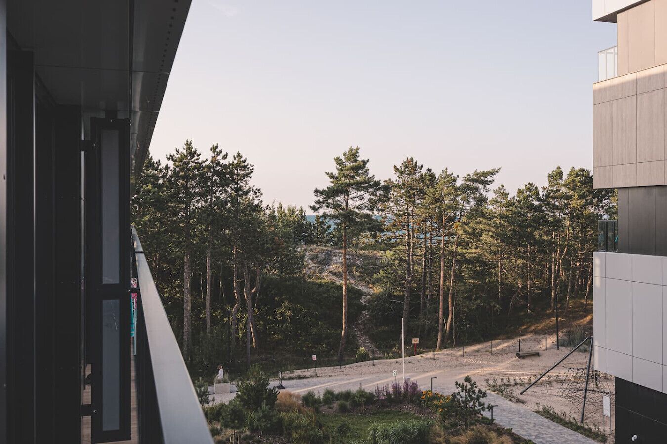 Un edificio moderno con vista su una zona boschiva e un sentiero sterrato.