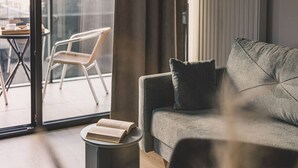 A modern living room with a grey sofa, a small round table with a book, and a chair.