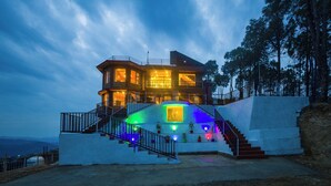 Une maison à plusieurs étages dotée d’un balcon, d’un escalier et offrant une vue sur le paysage environnant.