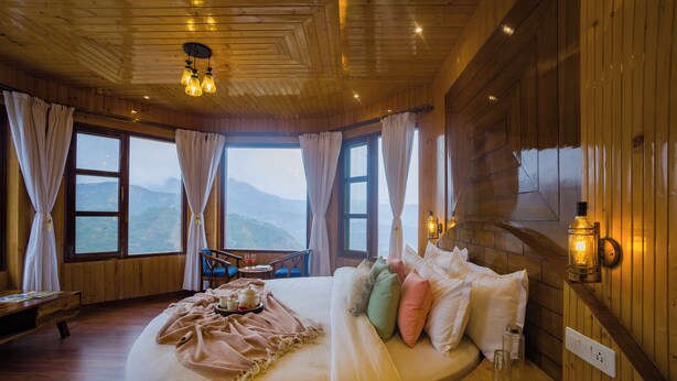 Une pièce en bois avec un grand lit, un banc et une table avec une lampe.