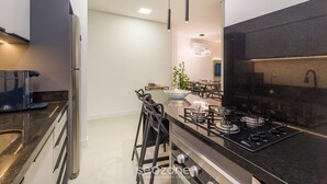 A modern kitchen with a black countertop, stainless steel appliances, and pendant lighting. - Apart in Cond. w/ Pool 400m From the Beach Tdb0101 (Florianópolis)
