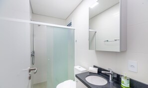 A modern bathroom with a glass shower enclosure, a white toilet, a black sink with a mirror above it, and a green bottle of hand soap on the counter. - Apart in Cond. w/ Pool 400m From the Beach Tdb0101 (Florianópolis)