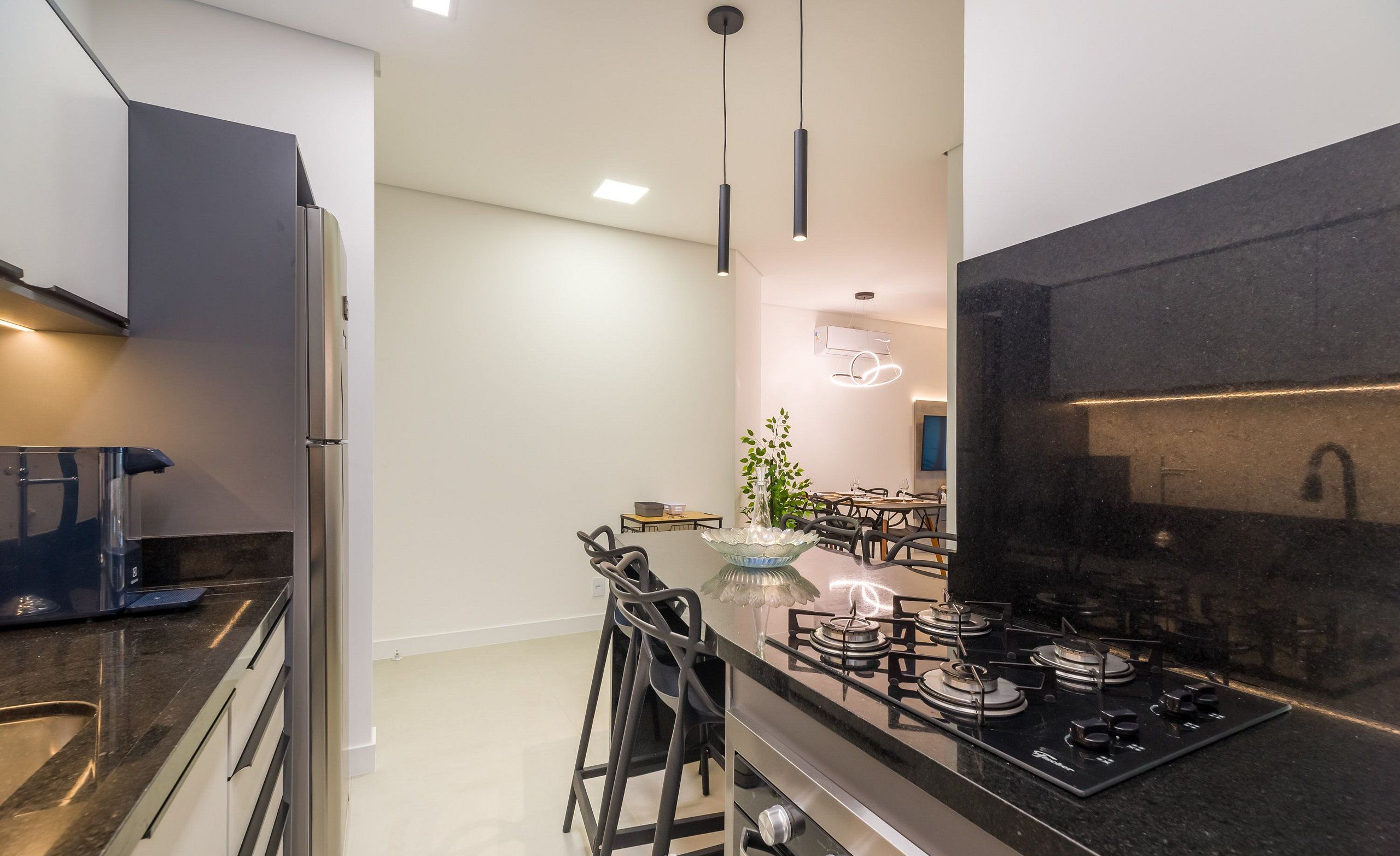A modern kitchen with a black countertop, stainless steel appliances, and pendant lighting.