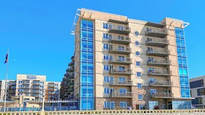 A multi-story hotel with balconies, a beachside location, and a clear blue sky. - Seaside Resort - 2 Bedroom 2 Bath - Assignment Q2 (Seaside)