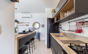 Cozinha moderna com ilha central, eletrodomésticos pretos e um suporte para panelas suspenso.