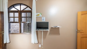 Une chambre dotée d’une grande fenêtre, d’un téléviseur à écran plat, d’un panneau indiquant la présence d’une connexion Wi-Fi et d’une porte en bois.