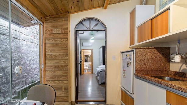 Un couloir étroit aux murs en bois, un coin cuisine doté de plans de travail en granit, et une salle de bain visible avec des toilettes et un lavabo.