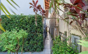 A narrow alleyway with dense foliage on both sides, leading to a gate. - Cozy House Near Ufsc - Tfl002 (Florianópolis)