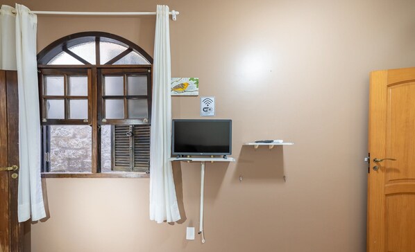 A room with a large window, a flat-screen TV, a Wi-Fi sign, and a wooden door.