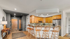 A modern kitchen with wooden cabinets, stainless steel appliances, and a central island with bar stools.