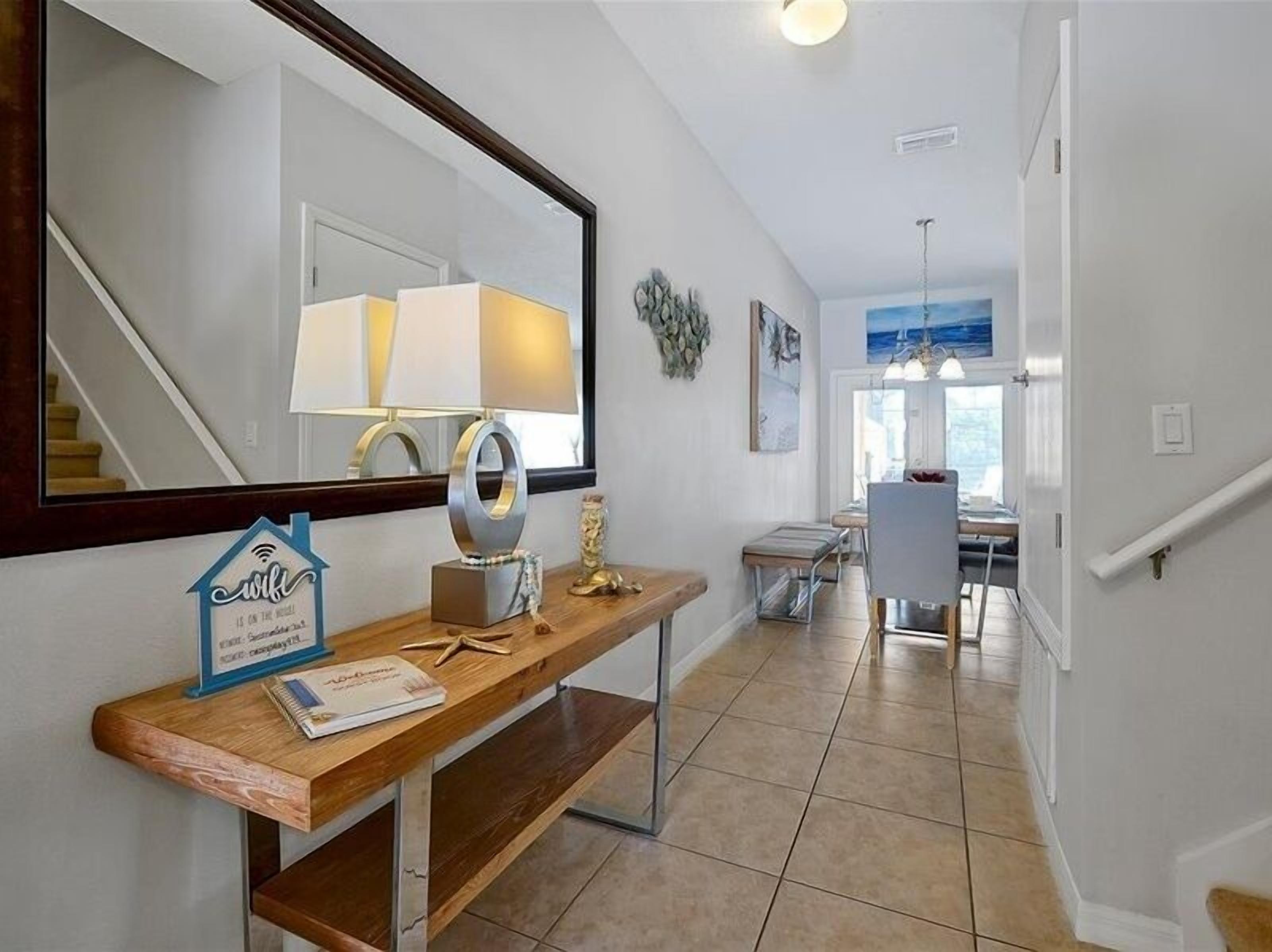 A modern hallway with a wooden console table, a mirror, and a decorative wall piece.