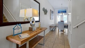 Un couloir moderne agrémenté d’une console en bois, d’un miroir et d’un élément décoratif mural.