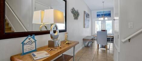 A modern hallway with a wooden console table, a mirror, and a decorative wall piece.