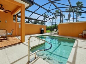 Area piscina con struttura in vetro, poltrone relax e ventola a soffitto.