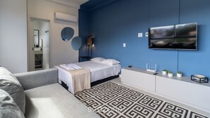 A modern bedroom with a bed, bedside table, TV, and a patterned rug. - Beautiful Studio Near Ufsc in Floripa Svo0506 (Florianópolis)