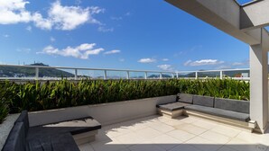 A rooftop terrace with a seating area, a view of the cityscape, and a clear sky. - Beautiful Studio Near Ufsc in Floripa Svo0506 (Florianópolis)