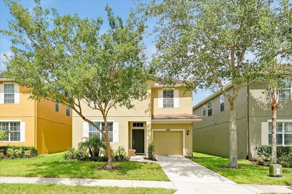 A two-story residential building with a beige facade, a front entrance, and a garage.