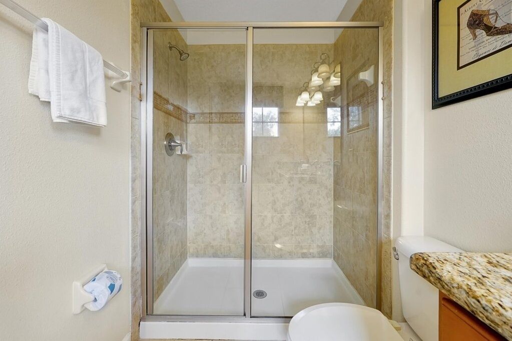 Een glazen douchecabine met een wit toilet en een wastafel aan de rechterkant.