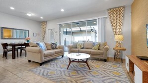 A living room with two sofas, a dining table, and a coffee table. - Magical Getaway Near Disney Private Pool + Resort Access, Bbq Grill! 4 Bedroom Townhouse (Kissimmee)