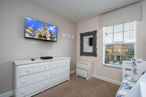A bedroom with a television mounted on the wall, a dresser with drawers, a mirror, and a window with blinds. - Family Pool Home Near Disney!! Modern Decor, Bbq ,resort W/ Tons Of Amenities! 6 Bedroom Home (Kissimmee)