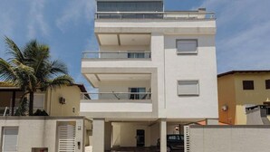 Un edificio de varios pisos con balcones, un acceso cubierto y una palmera cerca.