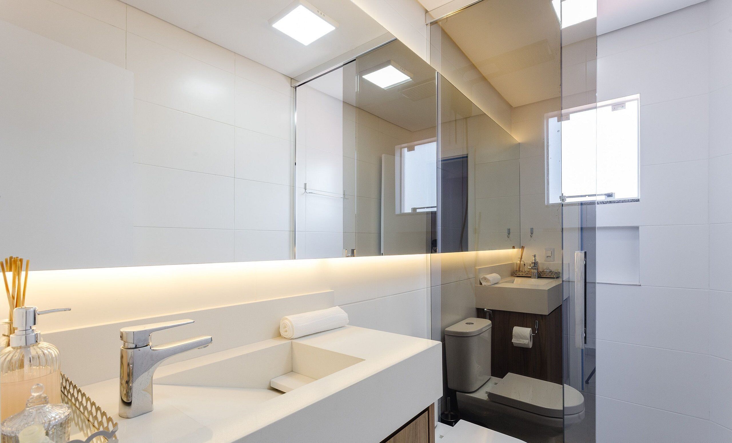 A modern bathroom with a large mirror, a white sink, and a glass shower enclosure.