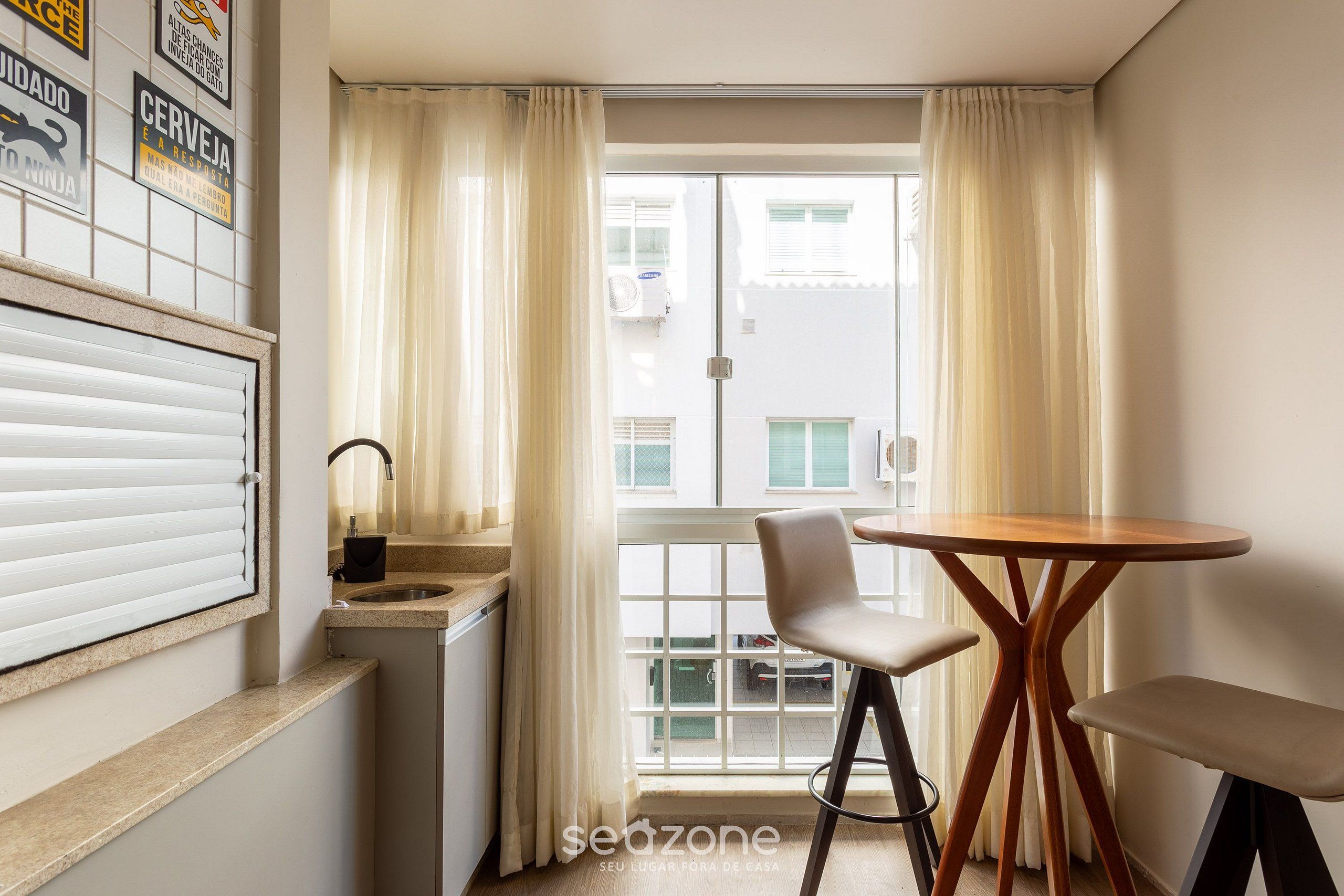 Une petite pièce avec une fenêtre, un lavabo, une chaise et une table.