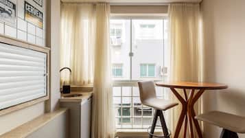 Une petite pièce avec une fenêtre, un lavabo, une chaise et une table.
