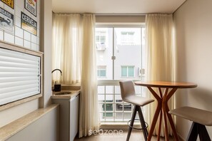 Una habitación pequeña con ventana, un lavabo, una silla y una mesa.