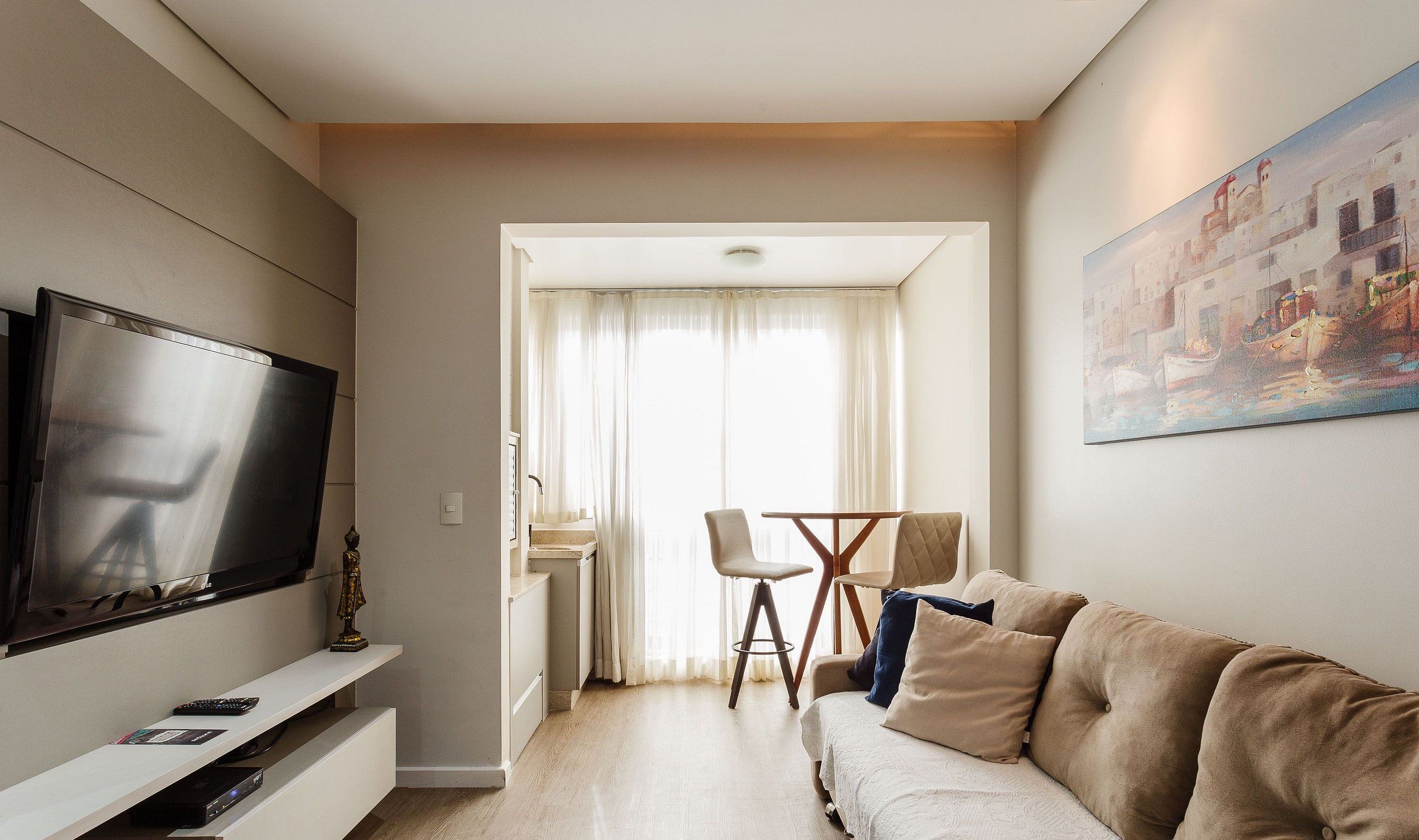Una sala de estar moderna con un televisor de pantalla plana, un sofá y una zona de comedor con una mesa y sillas.