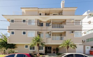 Un edificio residencial de varios pisos con balcones, unidades de aire acondicionado y una entrada protegida.