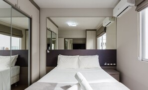 Habitación de hotel moderna con una cama grande, una mesita de noche, un espejo y un equipo de aire acondicionado.