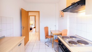 A compact kitchen with a stove, a dining table, and two chairs. - acora Bremen Garden Living the City (Bremen)