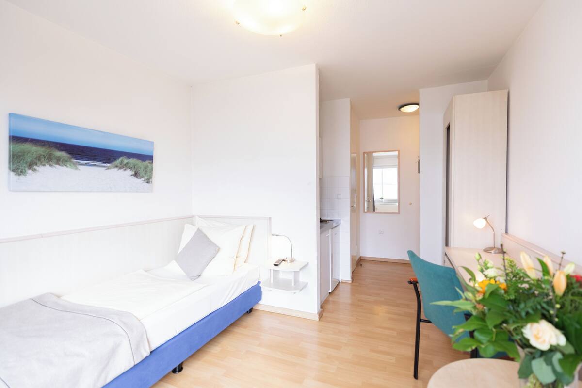 A modern bedroom with a bed, bedside table, and a small desk with a chair.