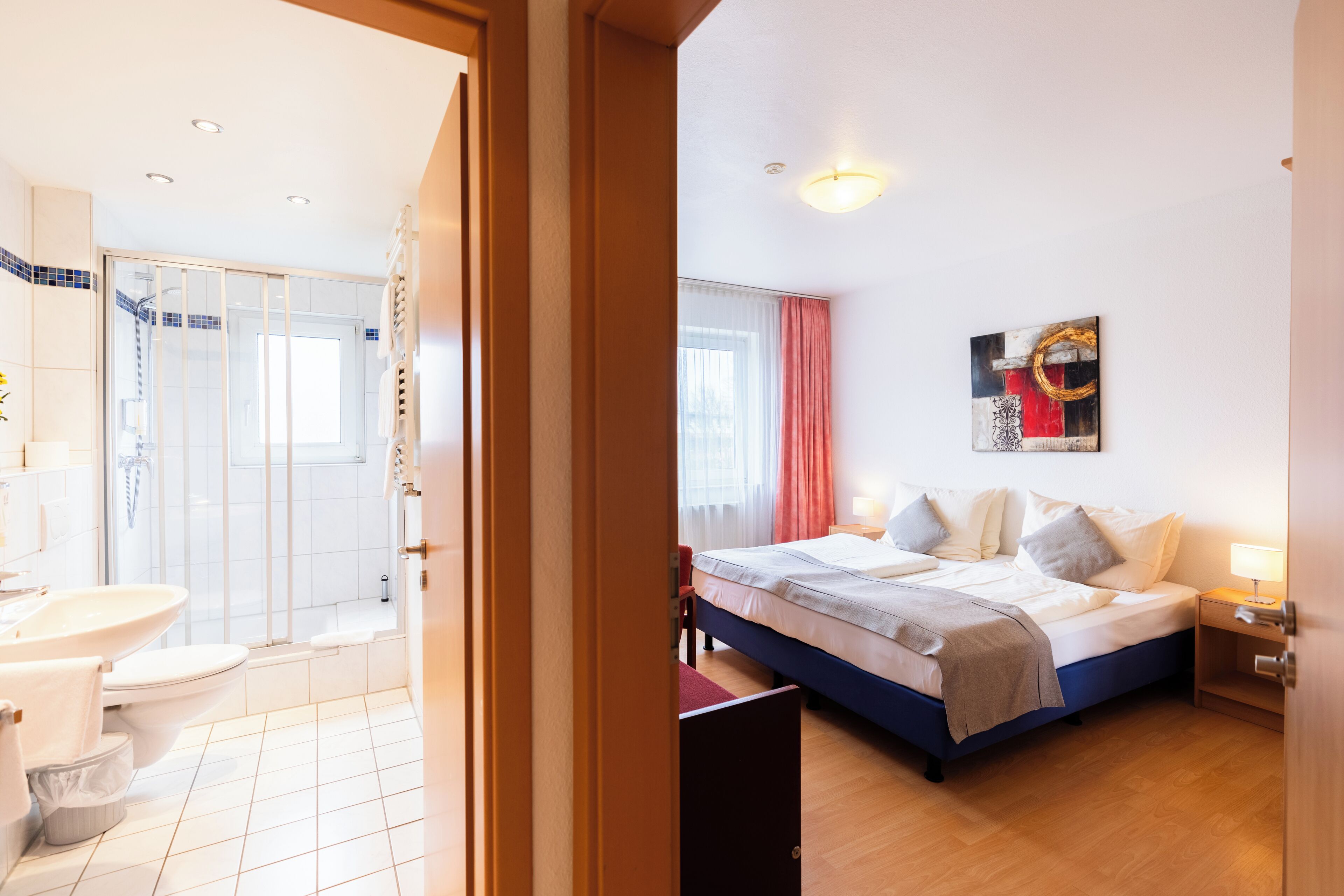 Une chambre d’hôtel avec un lit, une table de chevet et une fenêtre avec des rideaux.