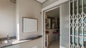 A kitchen with a sink, cabinets, and a sliding glass door leading to a dining area. - Apto espaçoso com piscina 750m da praia | CHR025 (Florianópolis)