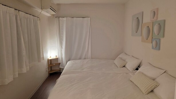 A bedroom with a large bed, a bedside table, a window with curtains, and wall-mounted artwork. - A cozy accommodation in Nakano City, 3 stops from Shinjuku, for 4 people (Nakano City)