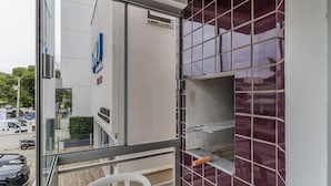 A balcony with a glass railing, a white chair, and a tiled wall.