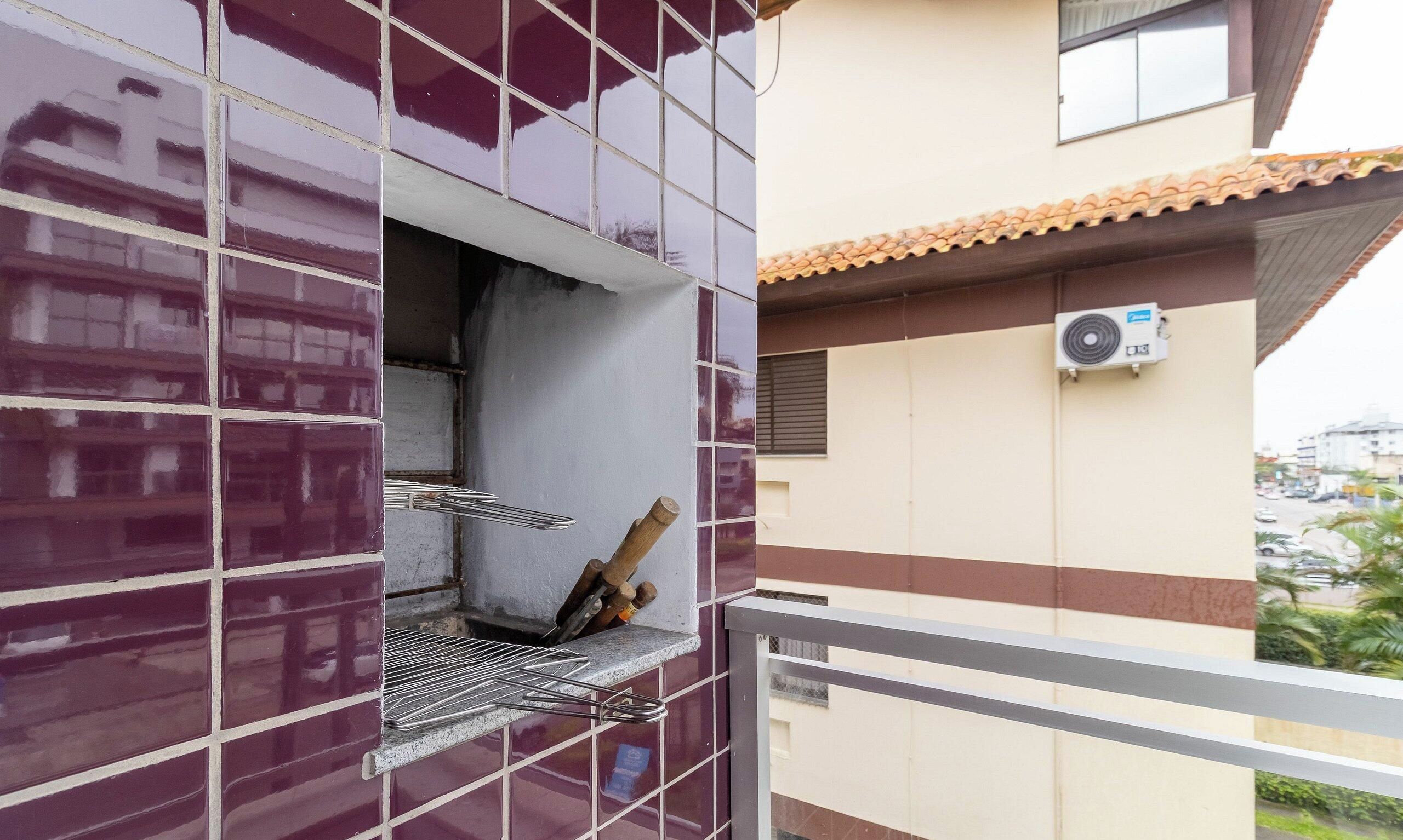 Un immeuble doté d’un balcon, d’une fenêtre avec une grille en métal et d’un appareil de climatisation fixé au mur extérieur.