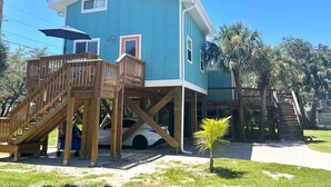 A two-story house with a wooden deck and a car parked in front.
