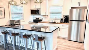 A modern kitchen with a central island, stainless steel appliances, and bar stools.