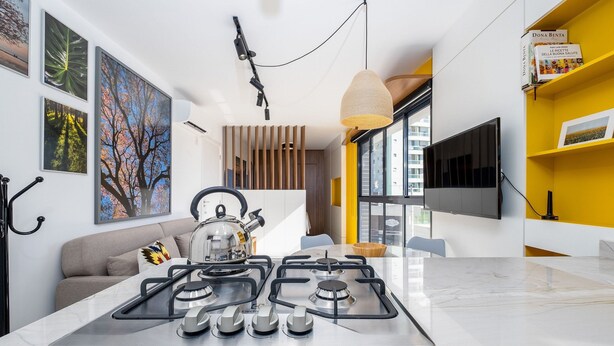 Una cocina moderna con estufa a gas, hervidor y comedor con una pared de acento amarilla.