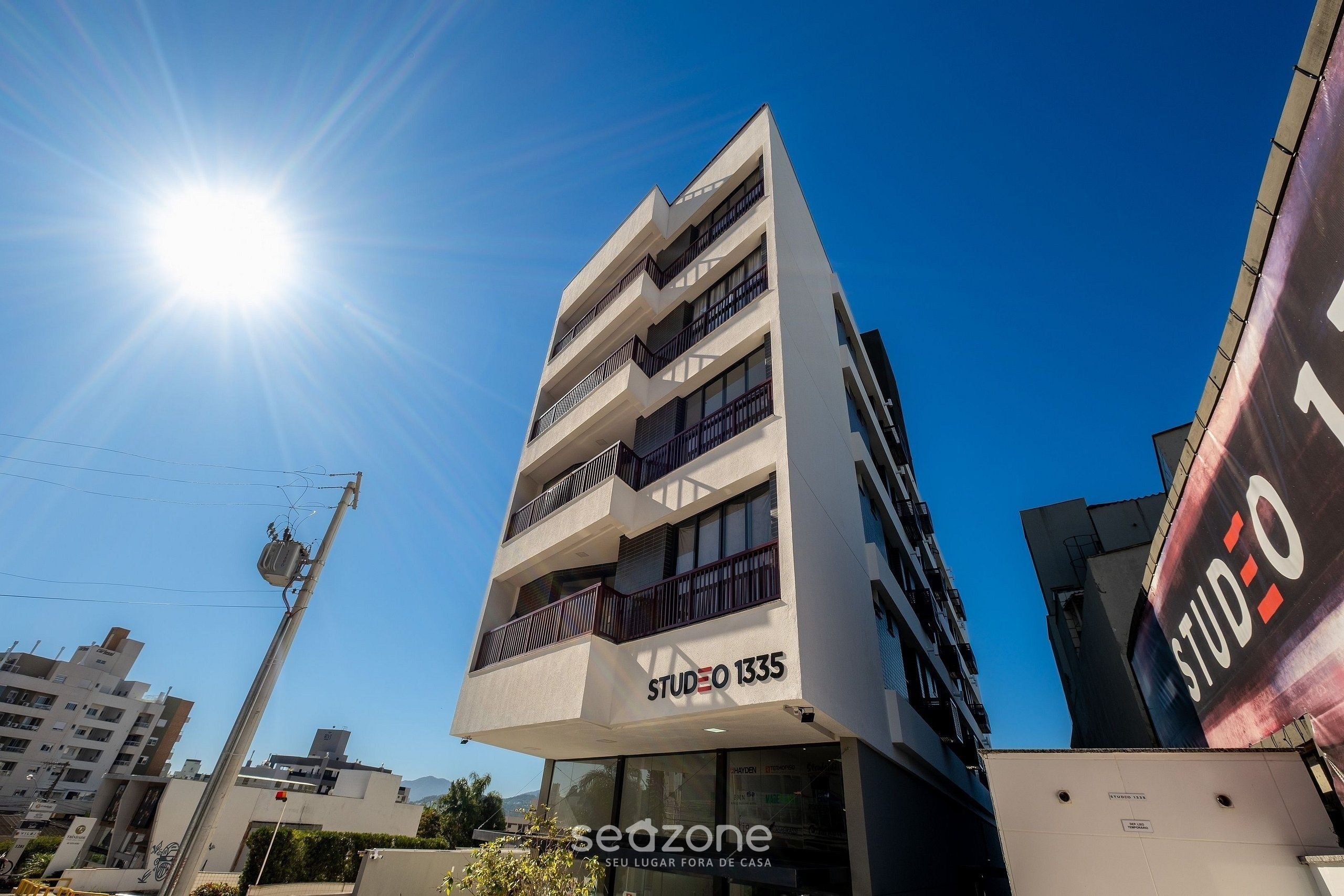 Un edificio de varios pisos con un letrero que dice 'STUDIO 1335' y 'SEUZONE SEU LUGAR FORA DE CASA'.