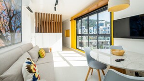 Una sala moderna con un sofá, una mesa de comedor y un ventanal con vistas a la ciudad.