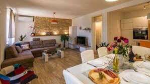 En moderne stue med sofa, sofabord og spiseplads dækket til et måltid.
