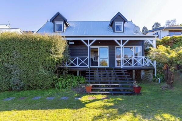 A two-story house with a balcony, a covered porch, and a well-maintained garden.