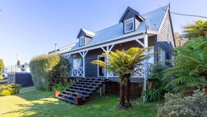 A two-story house with a steeply pitched roof, a front porch, and a small staircase leading to the entrance.