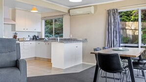A modern kitchen with white cabinets, a granite countertop, and a dining area with a table and chairs.
